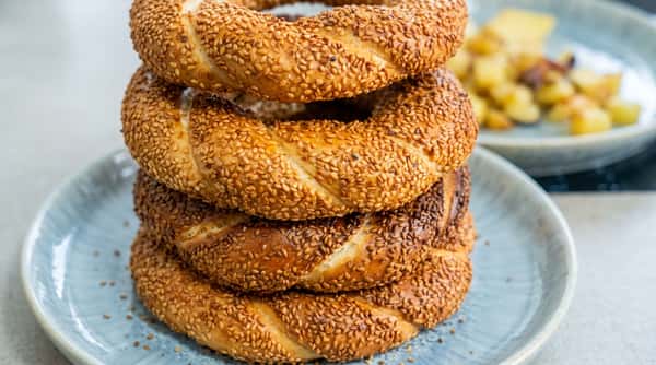 Stack of sesame-crusted Turkish simit bagels on a light blue plate.