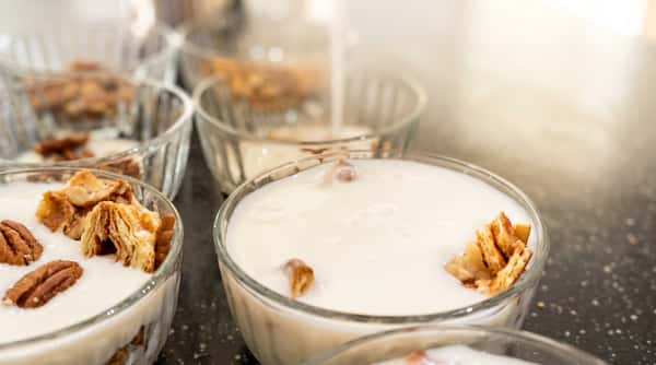 Individual glass bowls of white creamy dessert with diced toasted bread pieces.