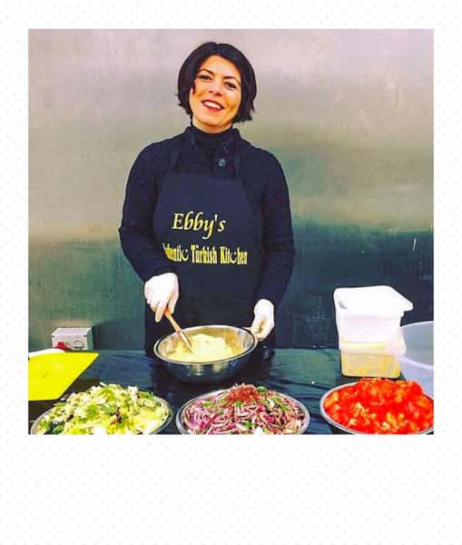 Chef preparing authentic Turkish dishes at Ebby's Turkish Kitchen, mixing fresh ingredients with chopped vegetables on a food preparation station.