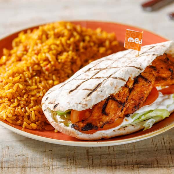 A grilled chicken flatbread wrap served with seasoned yellow rice on a rustic plate, featuring char-grilled chicken, fresh lettuce, tomato, and a creamy sauce, presented in a bright, appetizing food photography style.