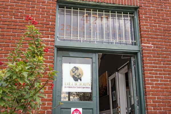 Green door under barred transom window at 420 22nd St South with "Delicious" wine bar sign and red brick exterior.