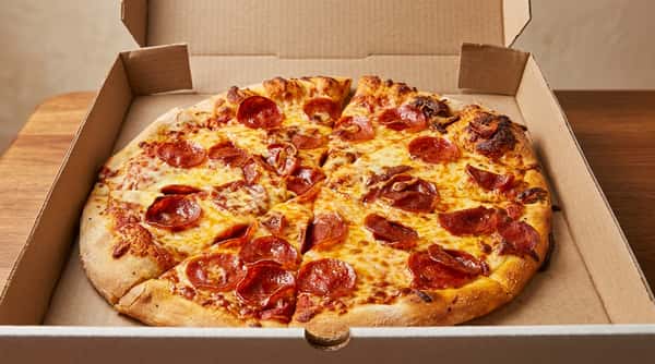 Pepperoni pizza with melted cheese and a golden crust, cut into slices inside a cardboard box.