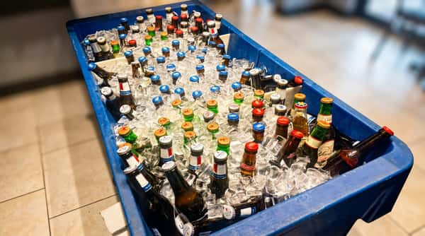 Hundreds of assorted beer bottles, including Miller, Michelob, and Bud Light, chill in a blue cooler filled with ice.