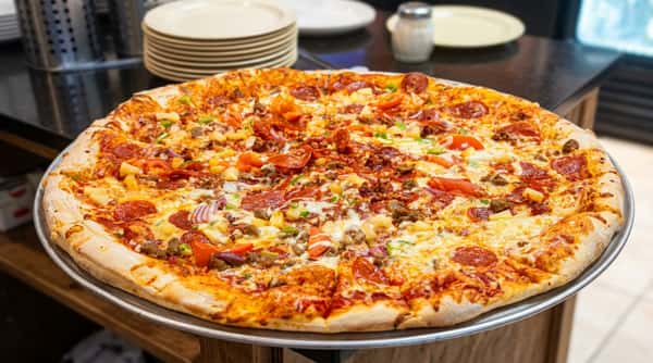 Large pizza topped with pepperoni, tomatoes, pineapple, ground meat, and green peppers on a metal tray.