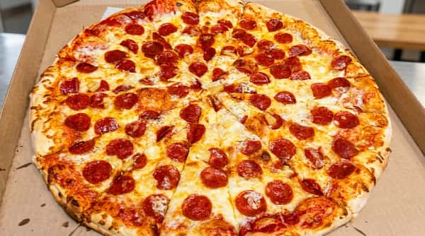 Pepperoni and pineapple pizza, sliced, in a cardboard delivery box.