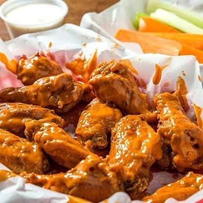 Spicy buffalo wings tossed in tangy hot sauce, served with ranch dip, carrot sticks, and celery—classic American bar food favorite.