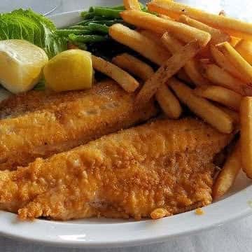 Crispy battered fish fillets served with golden French fries, lemon wedges, and a garnish of lettuce—classic fish and chips perfect for pub-style or seafood restaurant menus.