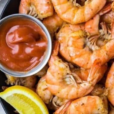 Plump steamed shrimp served with a side of classic cocktail sauce and lemon wedge—simple and savory seafood appetizer.