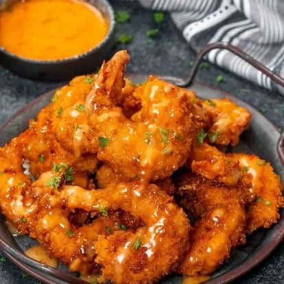 Crispy fried shrimp tossed in creamy sweet and spicy bang bang sauce, garnished with fresh parsley—popular appetizer with a zesty kick.