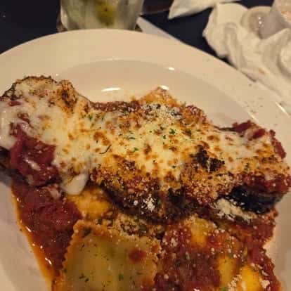 Baked eggplant parmesan smothered in marinara and mozzarella cheese, served with cheese-stuffed ravioli and sprinkled with parmesan—vegetarian Italian comfort food.