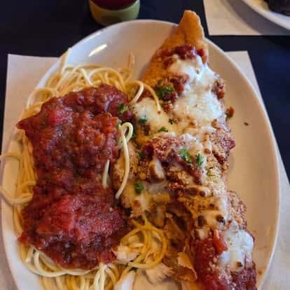 Baked chicken parmesan topped with marinara and melted mozzarella, served alongside spaghetti with rich tomato sauce—hearty Italian-American entrée.