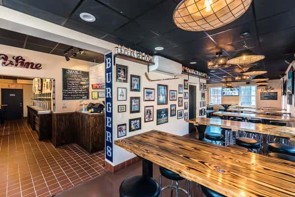 Spacious interior of Auggie's Draft Room with rustic wood tables, tap wall, sports-themed decor, and cozy lighting.