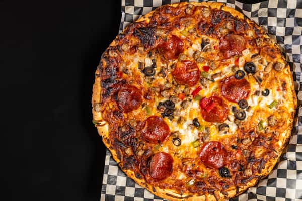 Top down view of Supreme Pizza on checkered paper