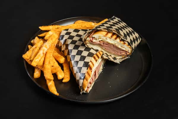 Italian Panini cut in half and wrapped in checkered paper with a side of fries