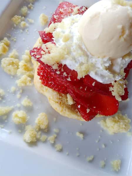 Vanilla cake topped with fresh strawberries, whipped cream, and a scoop of vanilla ice cream