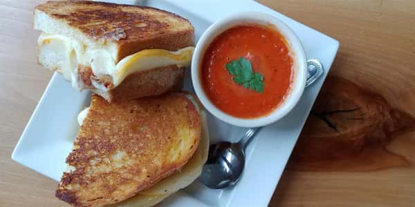 two halves of grilled cheese next to a cup of tomato soup