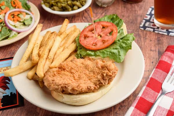 fried chicken sandwich with lettuce, tomato and a side of fries
