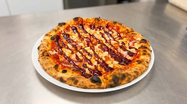 BBQ chicken pizza with diced chicken, red onions, mozzarella, and a generous drizzle of barbecue sauce.