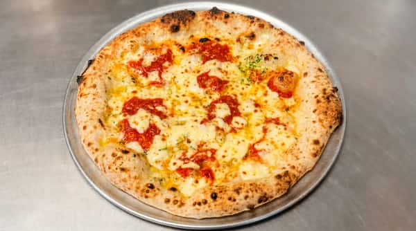 Neapolitan pizza with melted mozzarella, red tomato sauce, and charred crust on a metal tray.