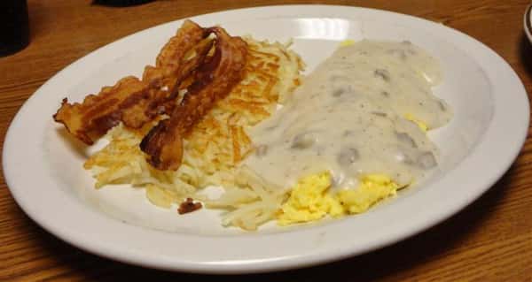 Hash browns served with bacon and scrambled eggs with gravy