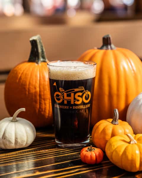 Pumpkin beer surrounded by pumpkins on a table