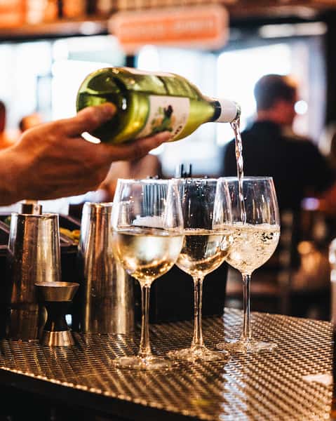 bartender pouring glasses of white wine