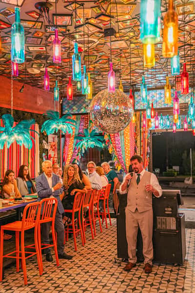 Private event setup inside O.H.S.O. Party House in Arcadia, Phoenix, with buffet tables, a full bar, colorful décor, hanging bottle lights, and a disco ball.