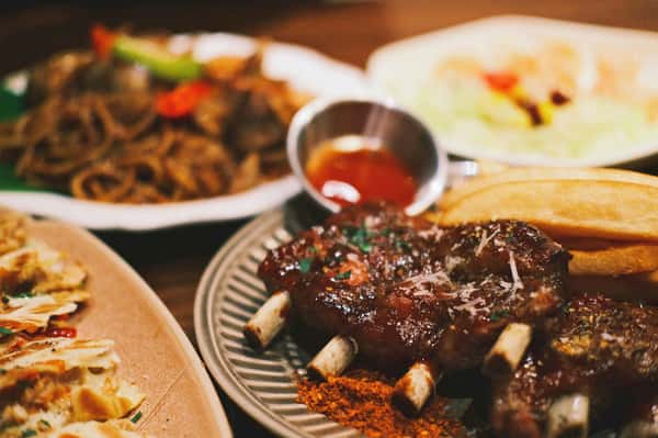 Close-up of a savory BBQ ribs platter with fries and dipping sauce, perfect for food enthusiasts.