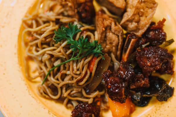 Delicious Asian dish featuring noodles, fried tofu, and rich sauces on a ceramic plate.