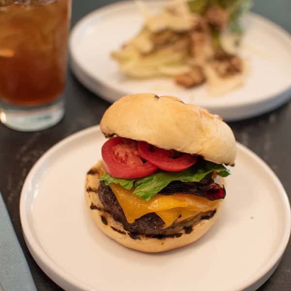 A grilled burger with melted cheddar cheese, lettuce, tomato, and a toasted bun.