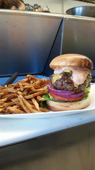 a burger with tomato, lettuce, cheese and a side of fries