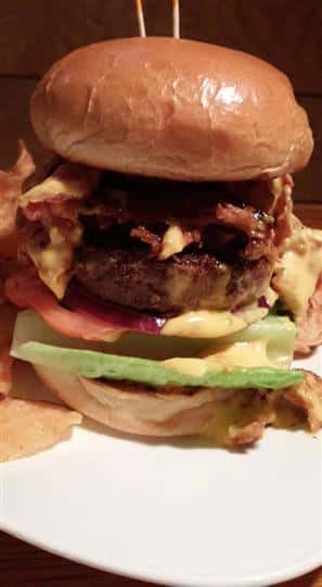 A burger with cheese, bacon, tomato and lettuce