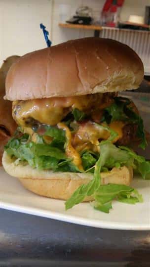 A burger with melted cheese, tomato and lettuce