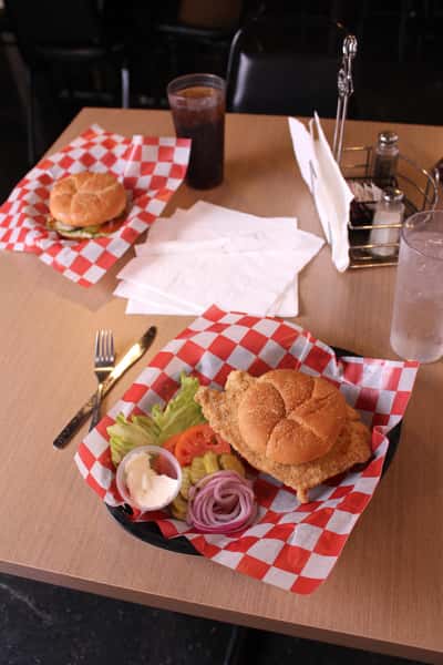 fried chicken sandwich with hamburger and cola in back