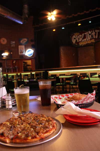 pizza pie with cola and beer in front of stage