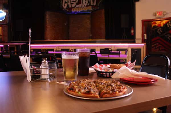 pizza pie with cola and beer in front of stage
