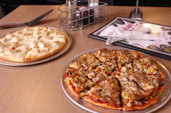 two pizza pies with utensils and menu