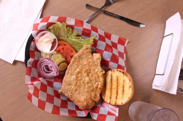 fried chicken sandwich with greens to the side