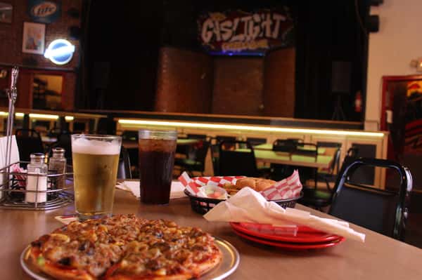 pizza pie with cola and beer in front of stage