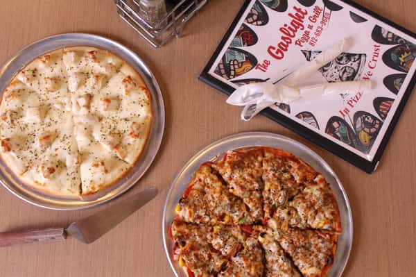 two pizza pies with utensils and menu
