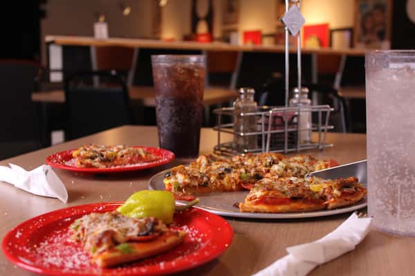 pizza pie with slices on plates