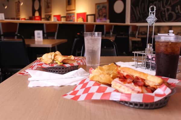 pepperoni hero with chips in a basket with cola and water