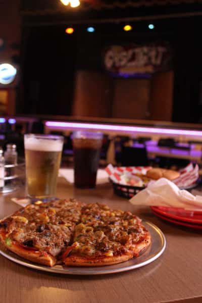 pizza pie with cola and beer in front of stage