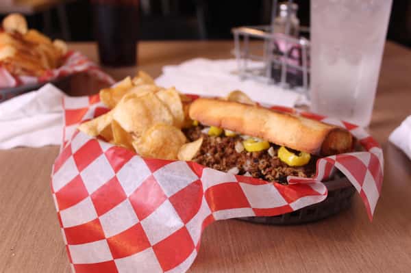 philly cheesesteak with chips in a basket with cola and water