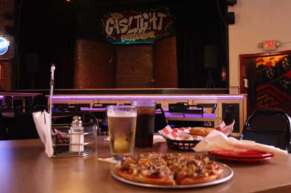 pizza pie with cola and beer in front of stage