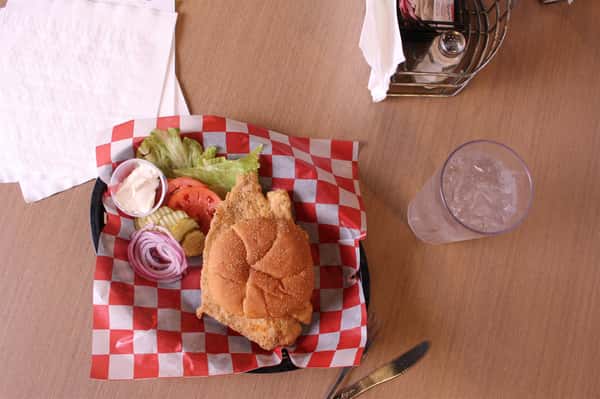 fried chicken sandwich with greens to the side