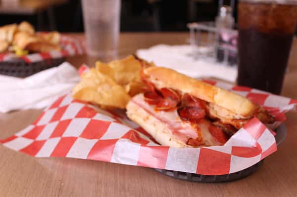 pepperoni hero with chips in a basket with cola and water
