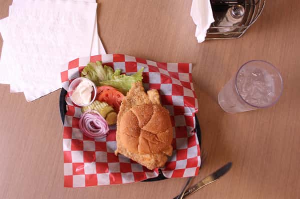 fried chicken sandwich with greens to the side