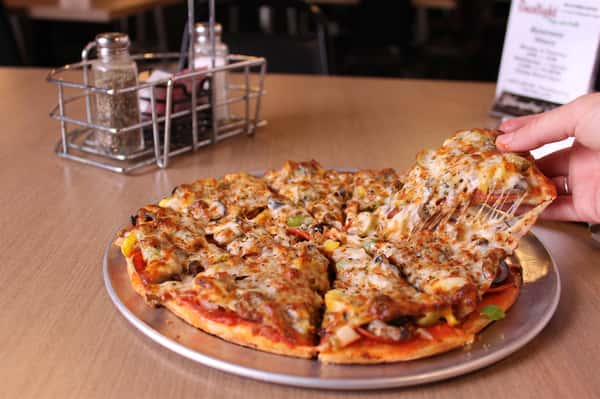 pizza pie next to salt and pepper shakers