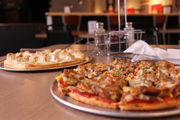 two pizza pies with utensils and menu